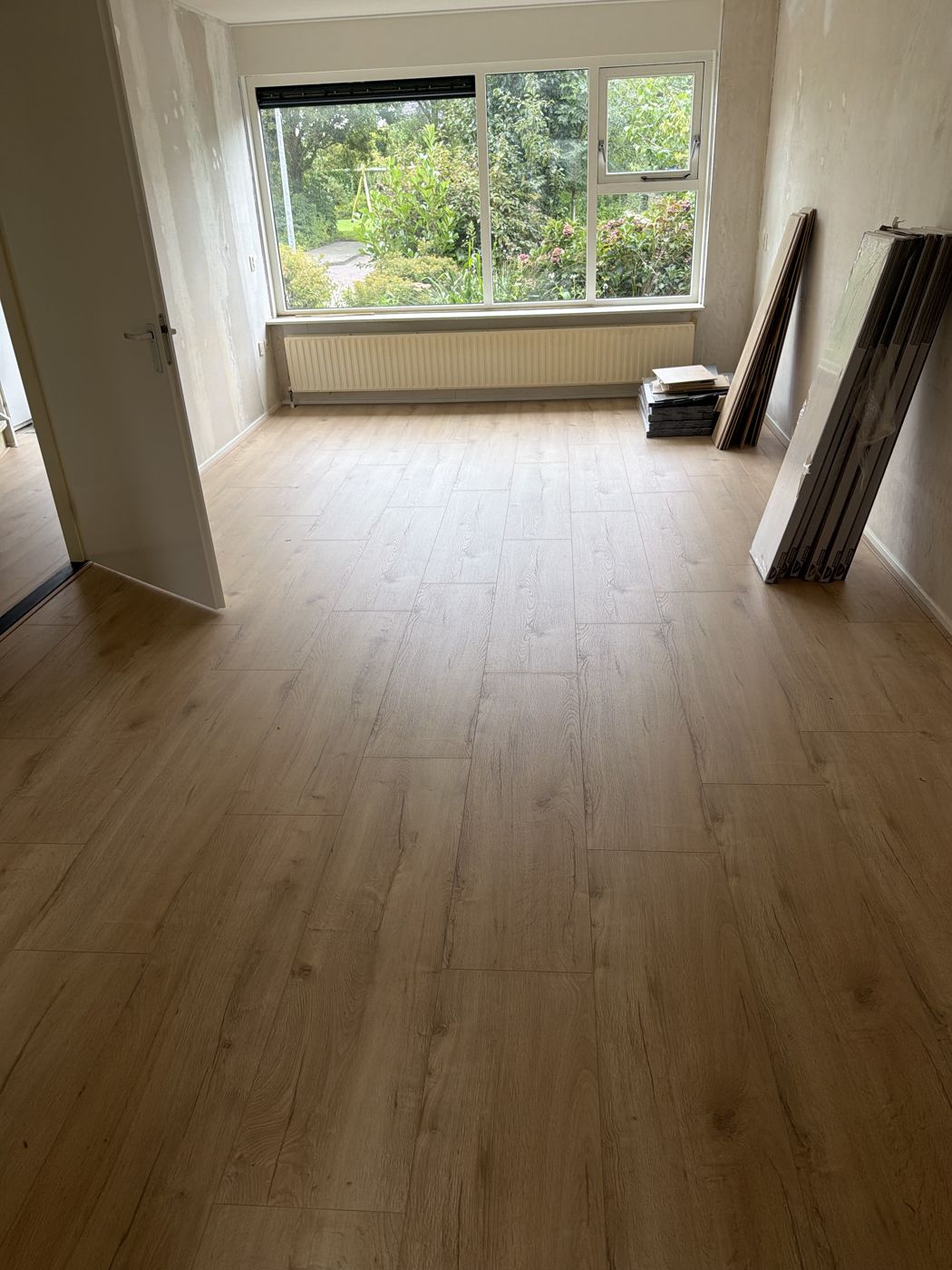 Lichte eiken laminaatvloer in een woonkamer met groot raam