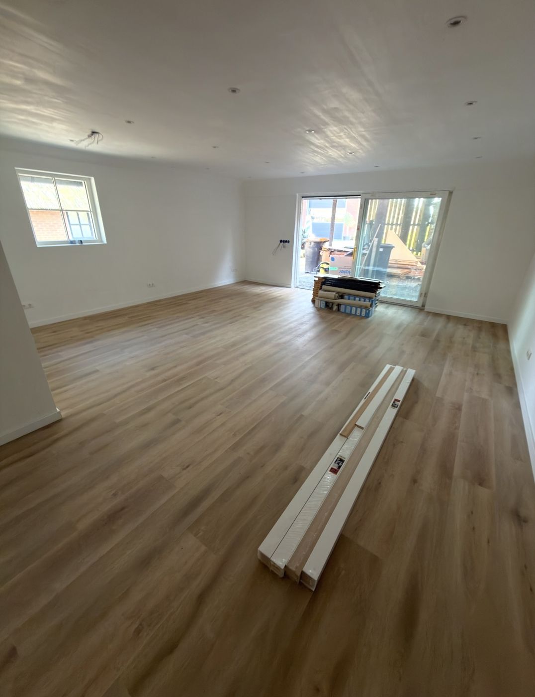 Ruime woonkamer met klik-PVC vloer en schuifpui